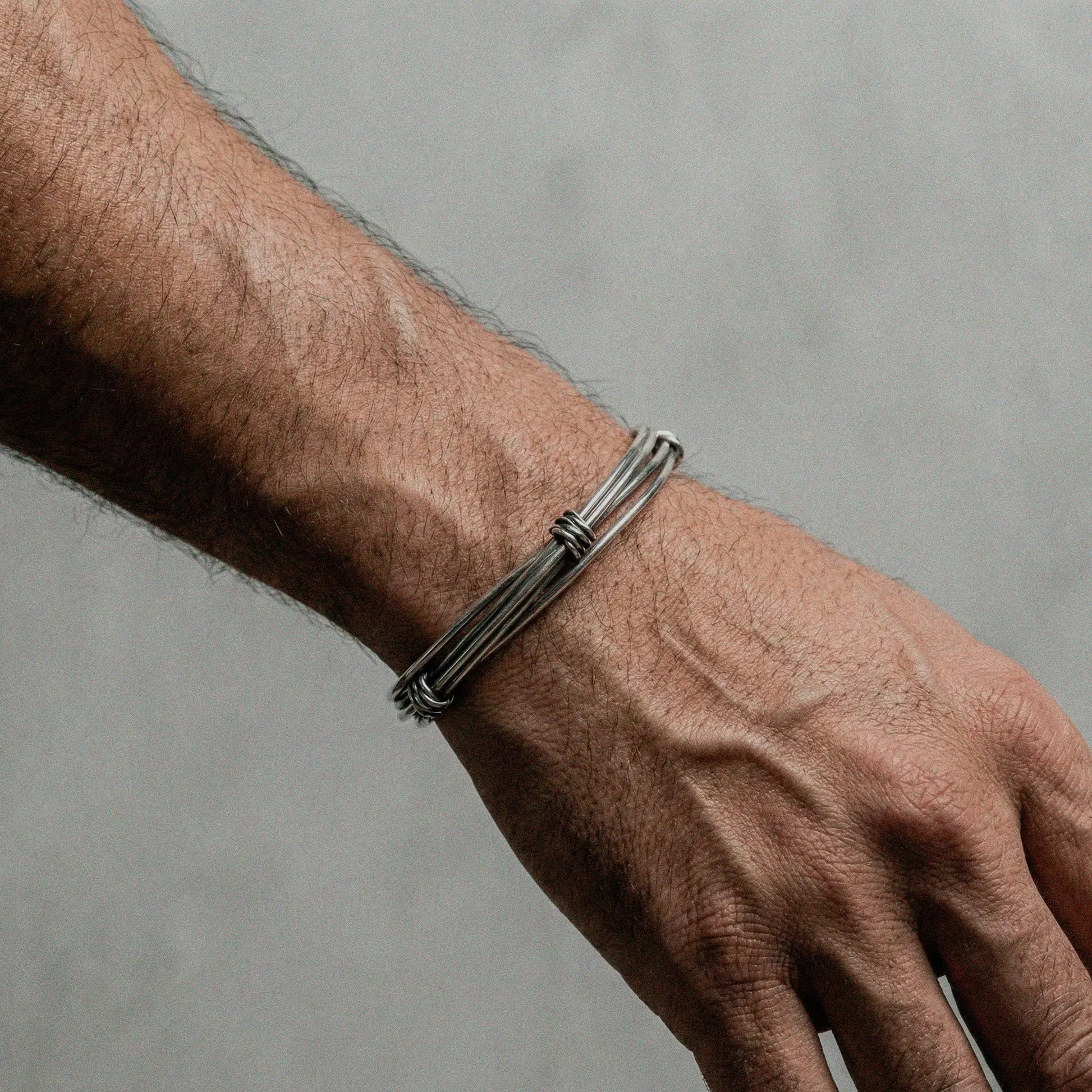 Silver bracelet on a person's wrist against a gray background