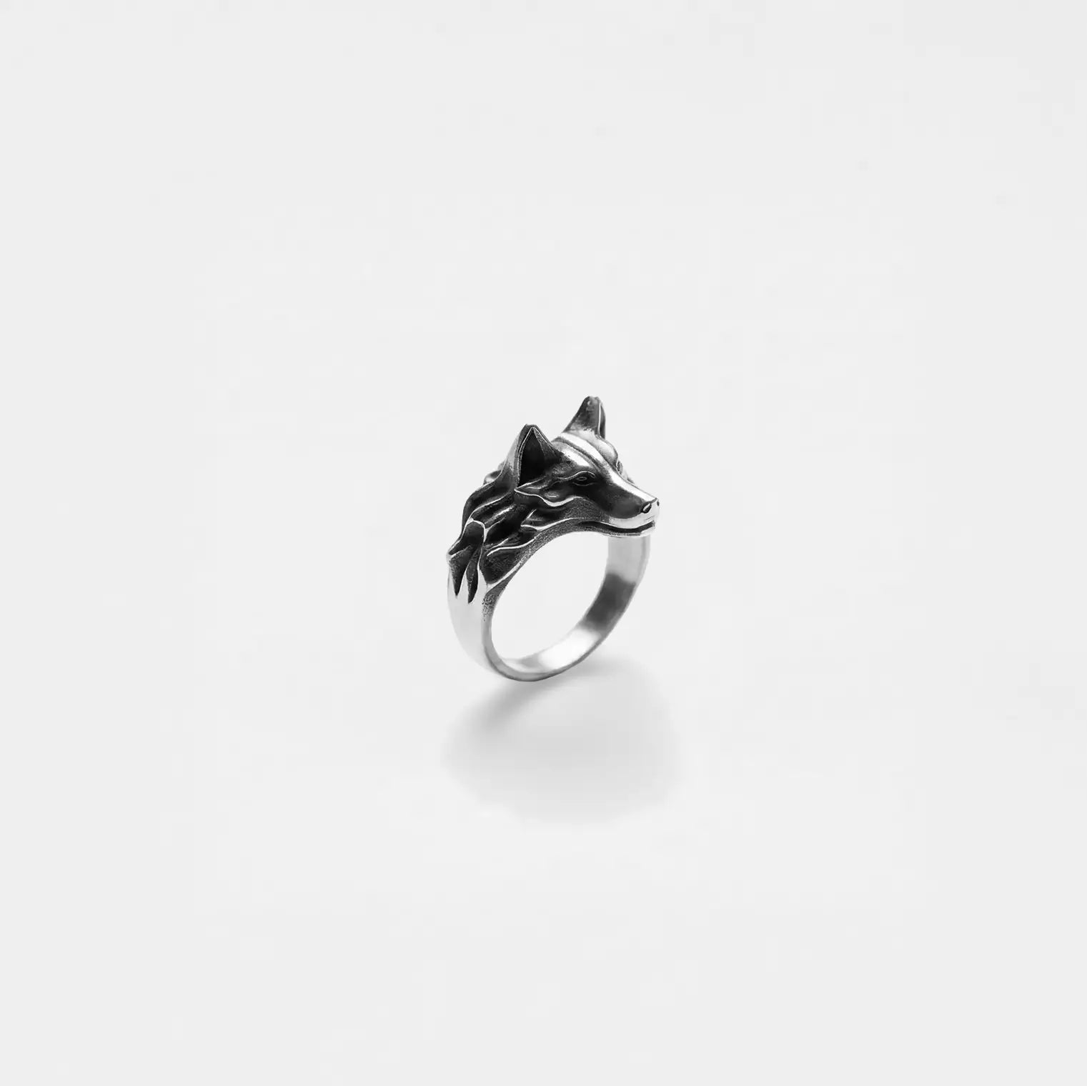 Silver ring with wolf design on a white background