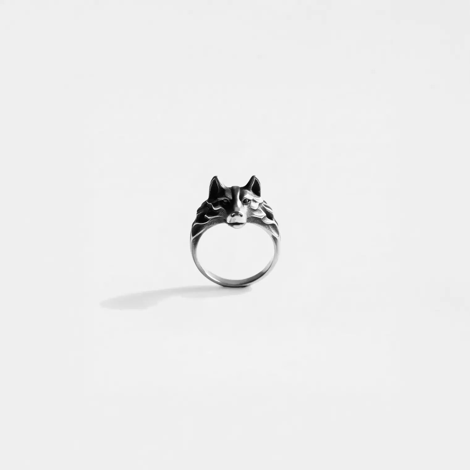 Silver ring with wolf design on a white background