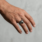 Hand wearing a silver ring with a WOLF design on a neutral background