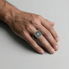 Hand wearing a silver wolf ring on a light gray background