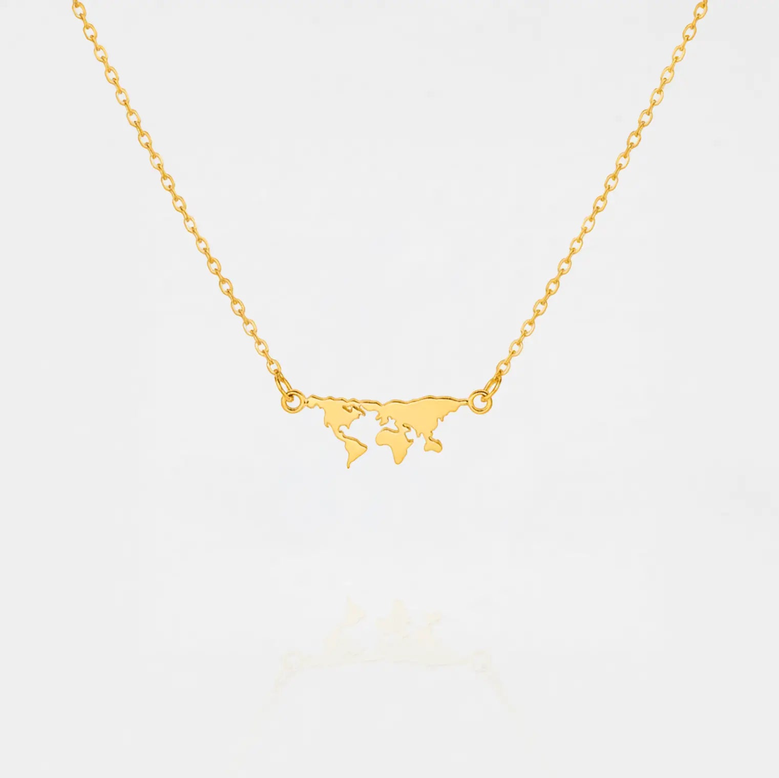 Gold necklace with a world map pendant on a light gray background