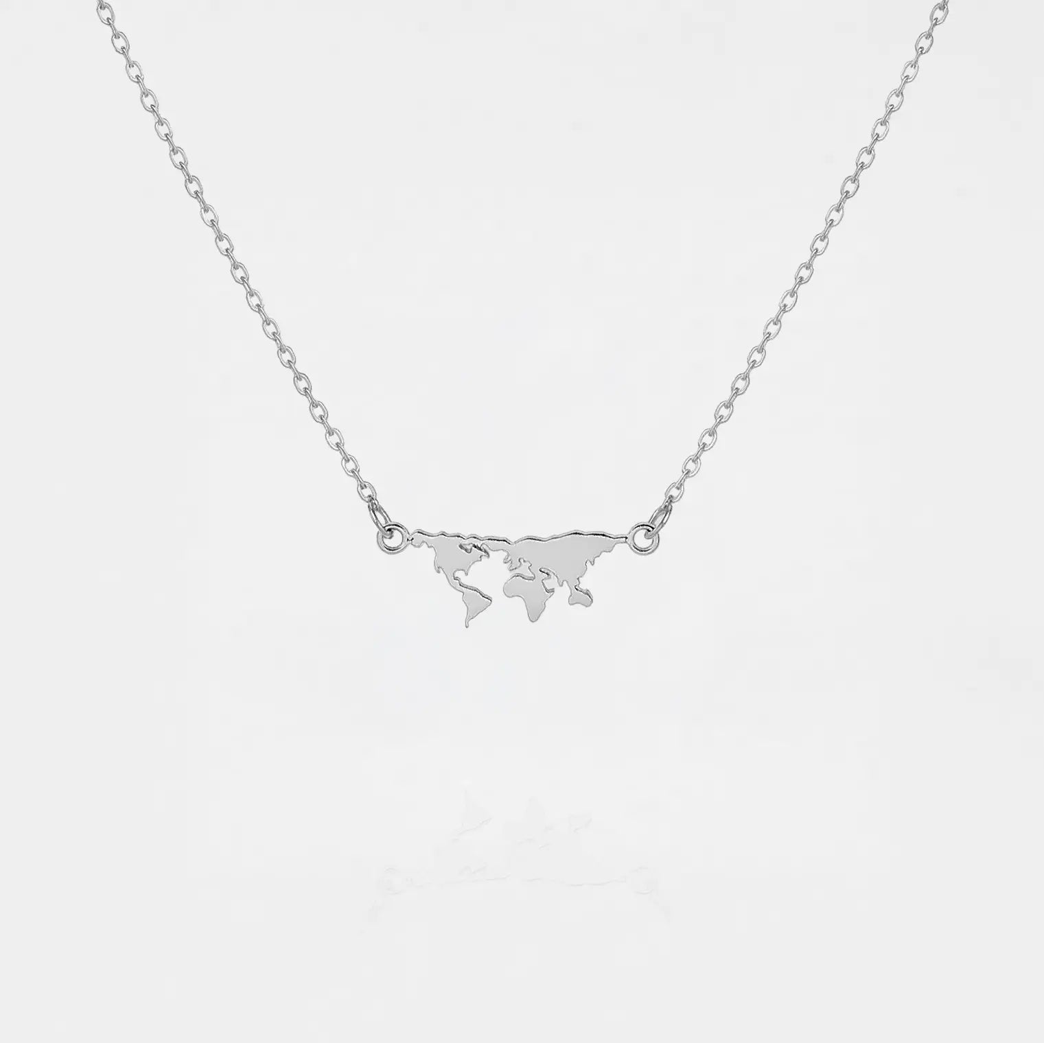 Silver necklace with a world map pendant on a light gray background