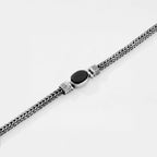 Bracelet with braided design and black stone on a white background