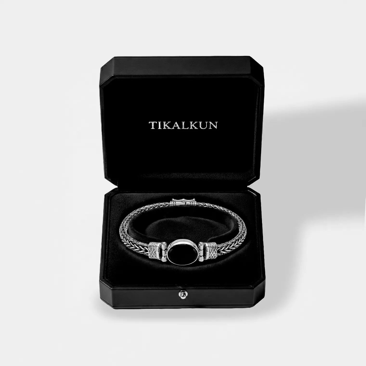 Silver bracelet with black center stone in a black Tikalkun box on a light gray background