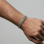 Silver bracelet on a wrist against a gray background