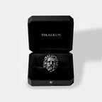 Silver ring with zeus face design in a black Tikalkun box on a light gray background