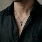 Man wearing a silver necklace featuring an anubis silver pendant.