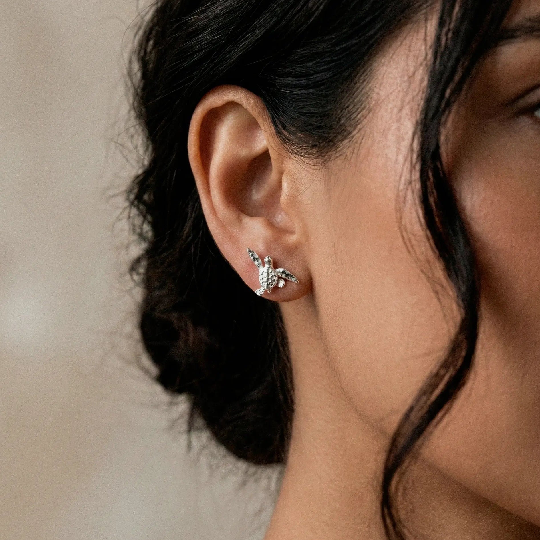 Close-up of a woman wearing a silver turtle earring