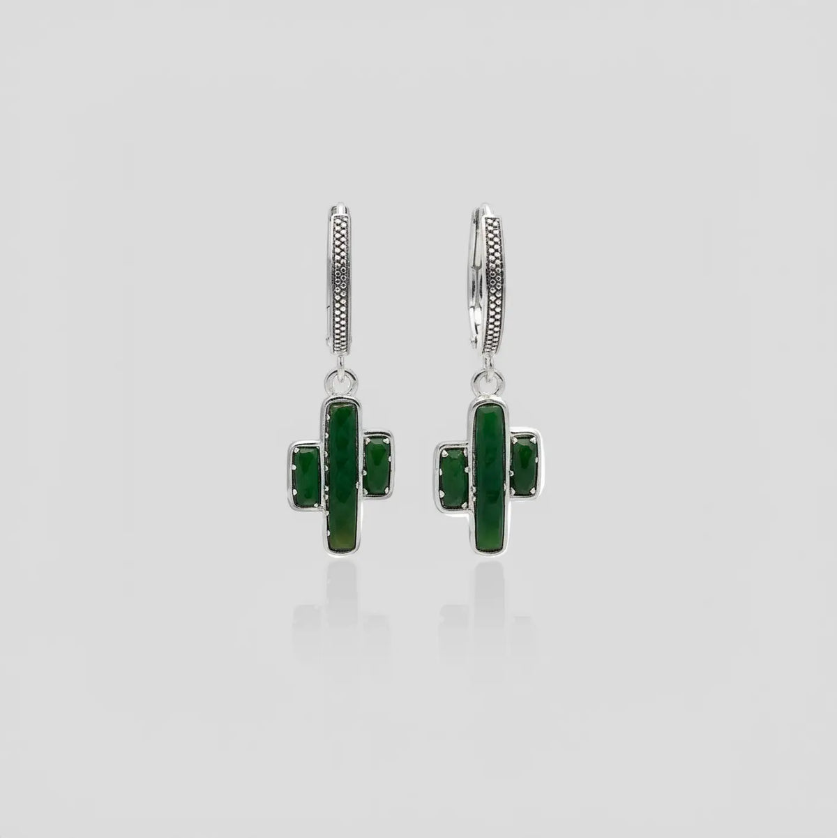 Pair of earrings cactus-shaped with jade stones on a light gray background