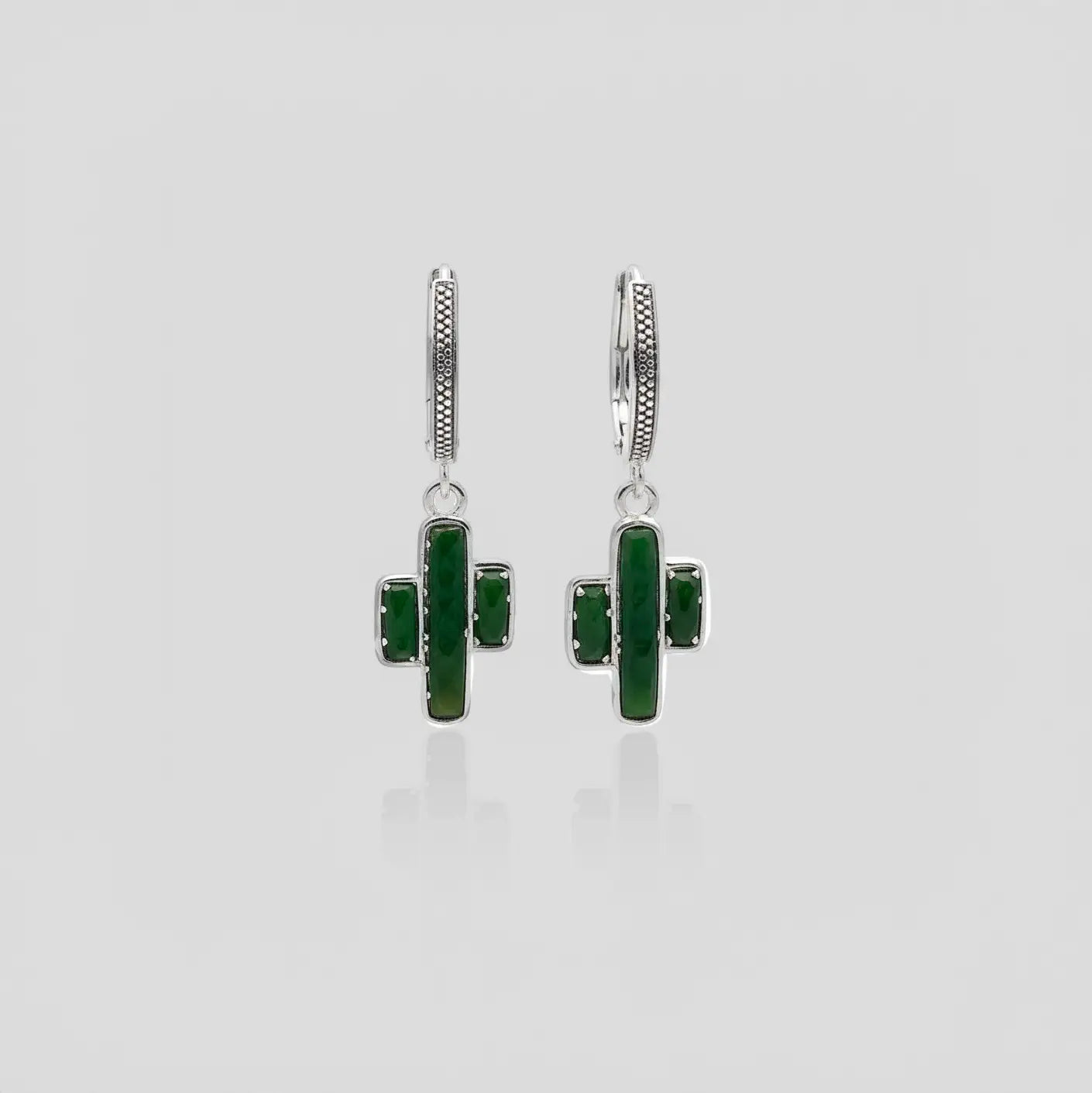 Pair of earrings cactus-shaped with jade stones on a light gray background