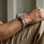 Close-up of a person's arm wearing a quetzalcoatl bracelet on a neutral background