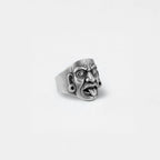 Silver mayan mask-like ring on a light gray background