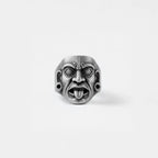 Silver mayan mask-like ring on a light gray background