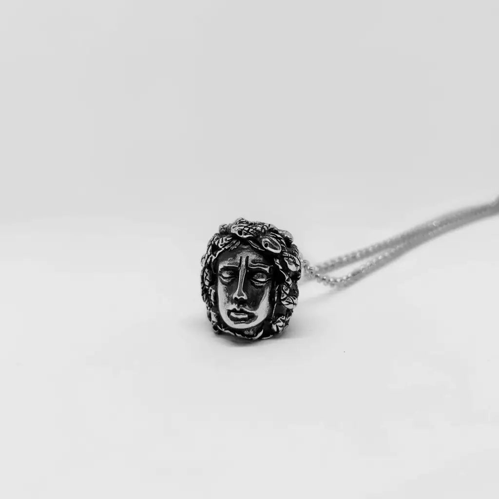 Silver necklace with a Medusa face pendant on a white background