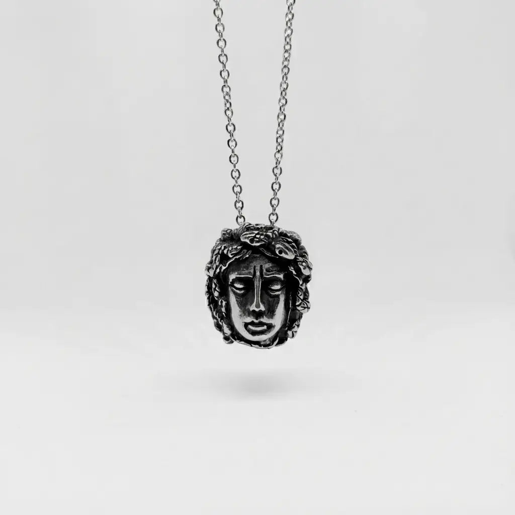 Silver necklace with a Medusa face pendant on a white background