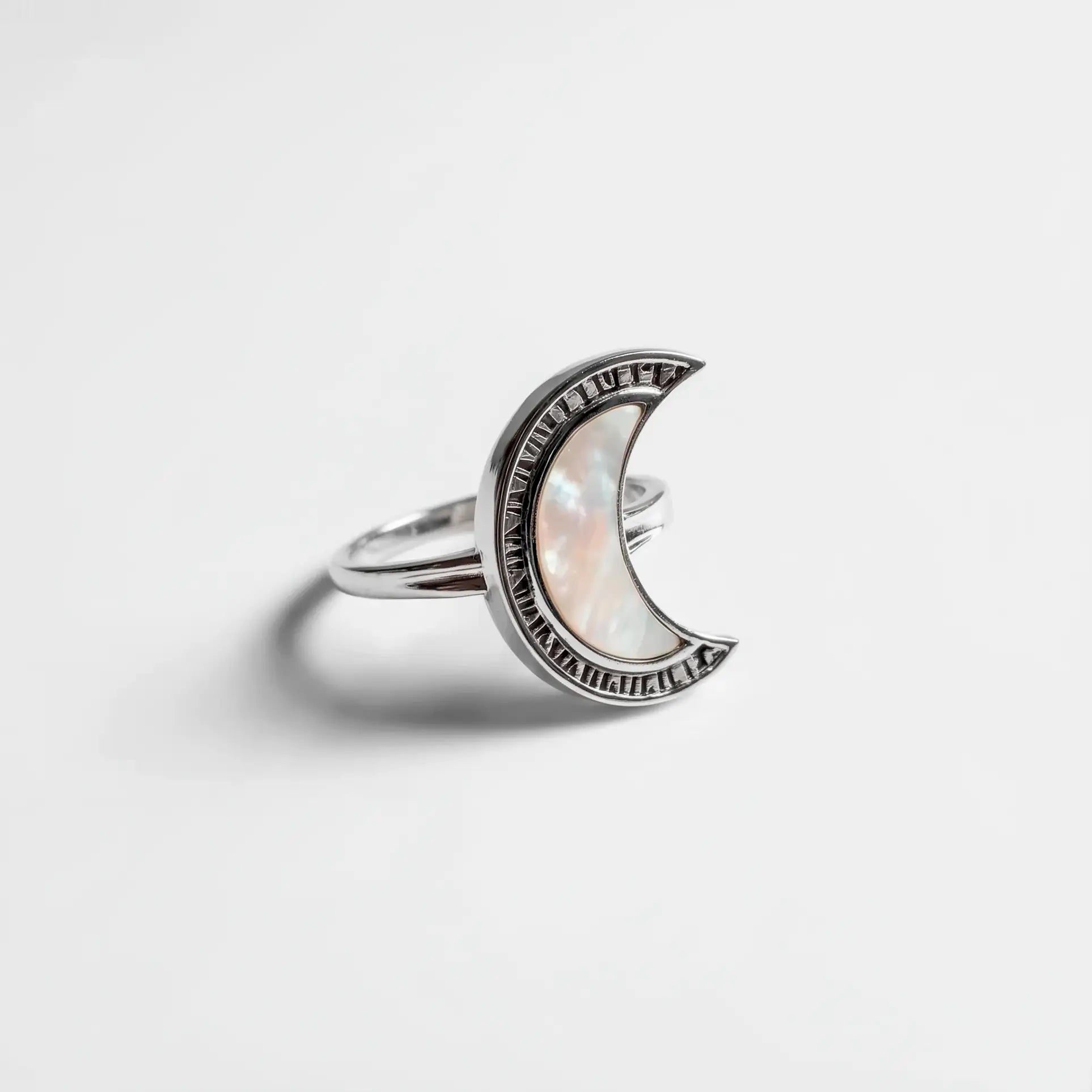 Silver crescent moon ring with a clear gemstone on a light gray background