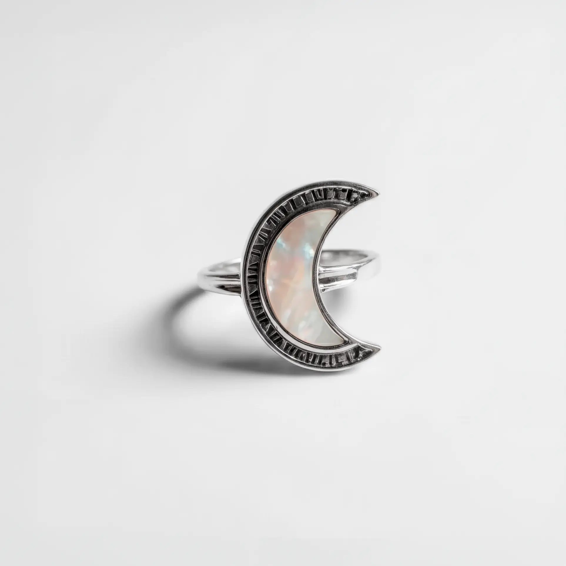 Silver crescent moon ring with a clear gemstone on a light gray background