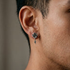 Close-up of a person wearing a silver rose-shaped earring with a leaf detail.