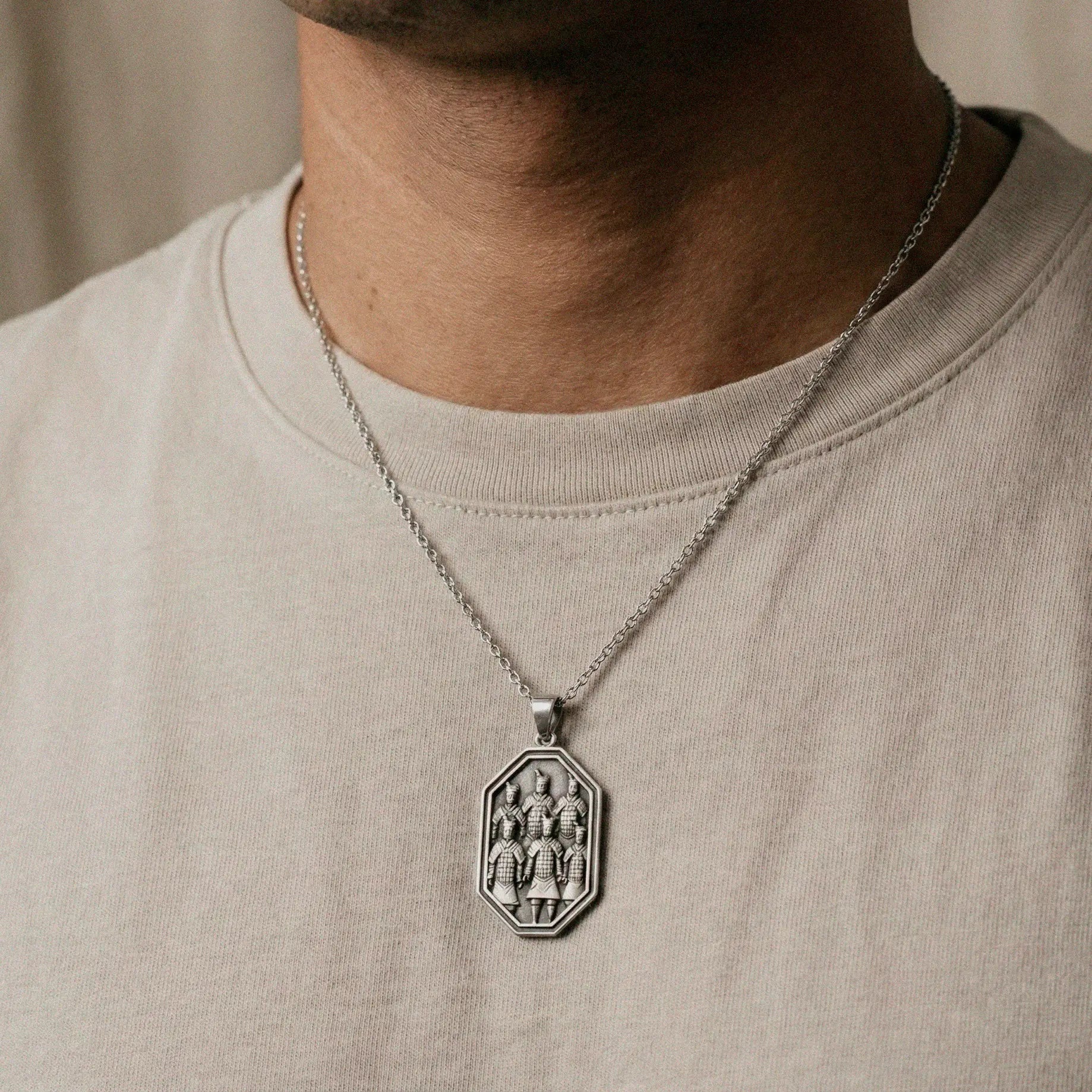 terracota's army Silver pendant worn by a person on a beige background