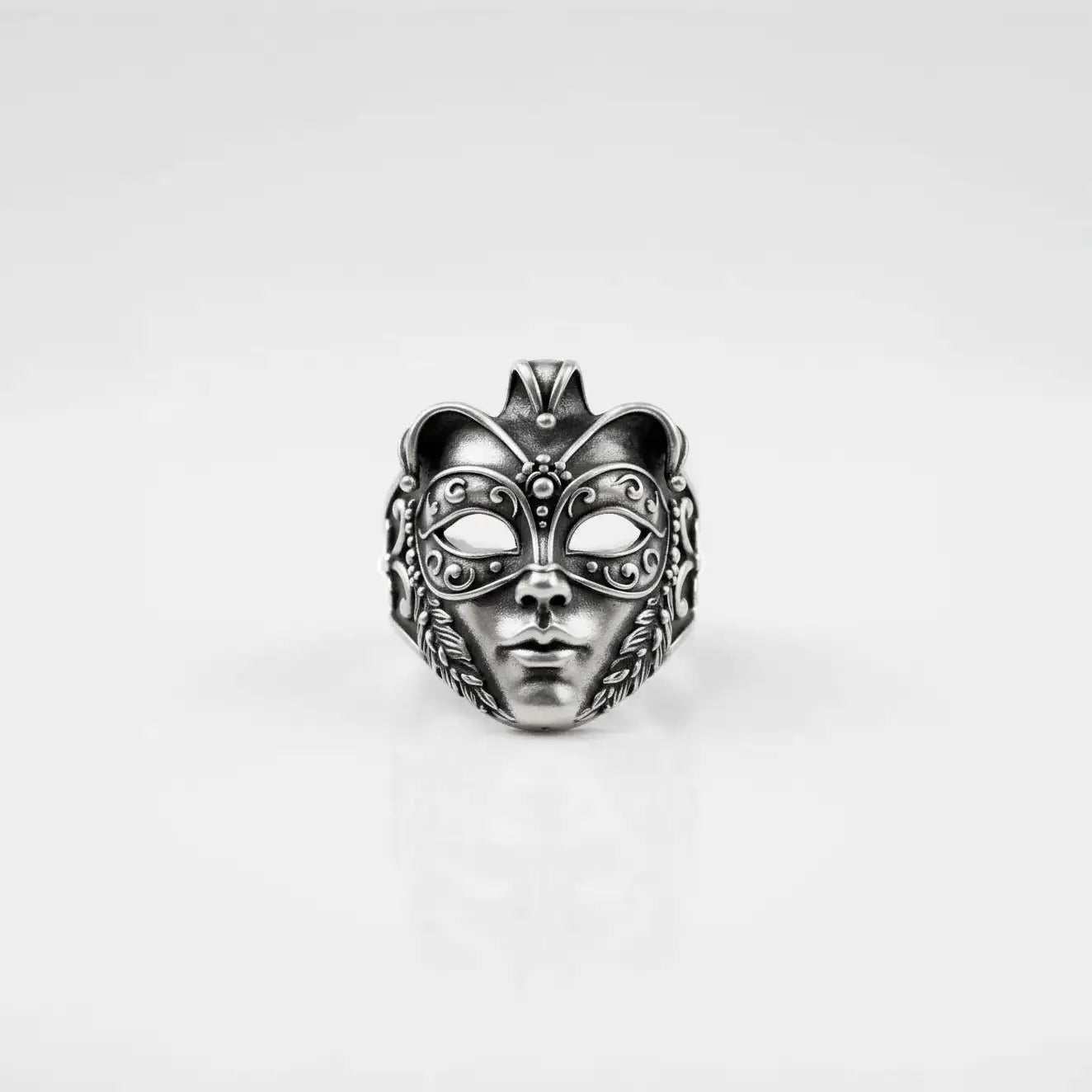 Silver venetian mask ring with intricate designs on a light gray background