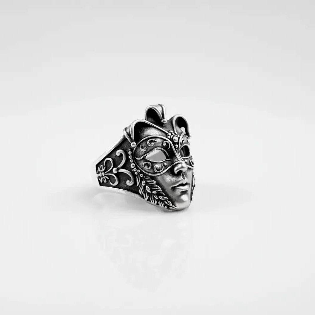 Silver venetian mask ring with intricate designs on a light gray background