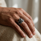 Hand wearing a silver volcano ring on a textured surface